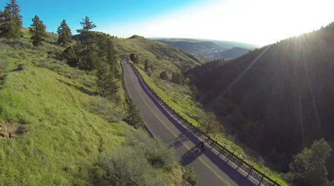 Aerial shot of man riding motorcycle on beautiful mountain road into sunrise. Stock Footage