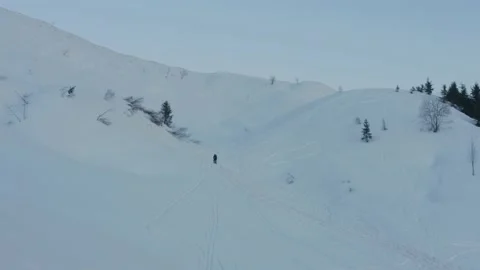 Aerial shot of a man walking alone in the snow at dusk, in Switzerland Stock Footage 196888145