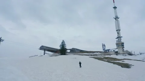 Aerial shot of a man walking alone in the snow to a ski resort, in Switzerland Stock Footage 196891730