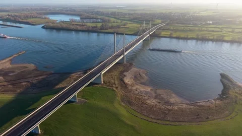 Aerial shot of a modern cable stayed bridge crossing a wide river. Industrial Video stock 329428888