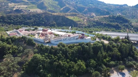 Aerial shot of a monastery on a green hill with busy highway traffic Stock Footage 344105251