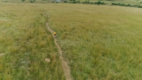	Aerial shot of a mountain biker on a path in a field Stock Footage 89333468
