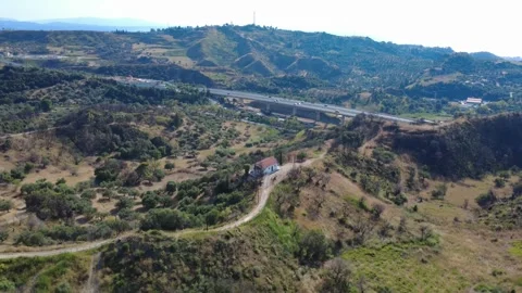 Aerial shot of a mountain chapel with a distant highway valley bridge Stock Footage 344105387