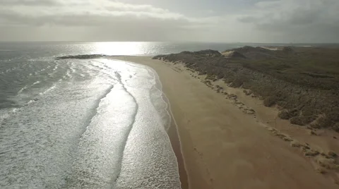 Aerial shot moving along empty sandy beach at sunset Video stock 65431283