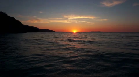 Aerial shot of ocean during sunset from sun towards beach Stock Footage 47488698