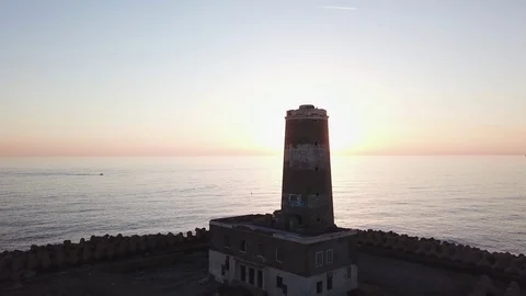 Aerial shot of an old abandoned lighthouse on the sea against the sunset Stock Footage 98317087