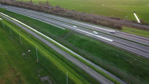 Aerial shot over a highway with cars and a yellow train passing by, 4K Stock Footage