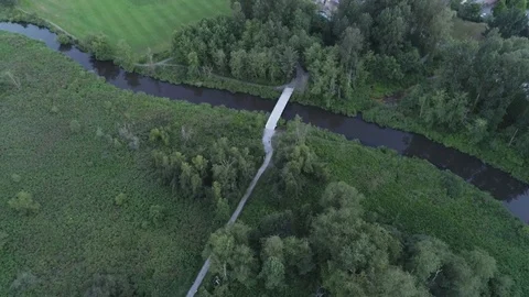 Aerial Shot Over Path And Bridge Over River In Public Park Beside Sports Fields Video stock 100532257