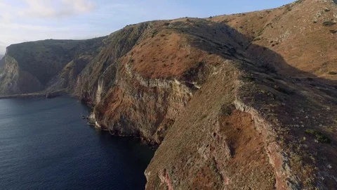 Aerial shot overlooking massive cliffs by the ocean, slowly moving forward. 库存影片 89412397