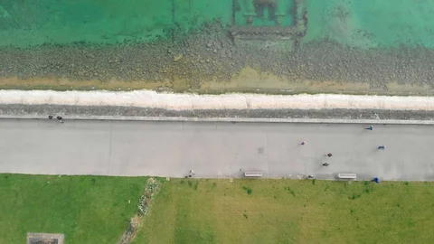 Aerial shot of people walking on the footpath with lake and grass Stock Footage 127890153