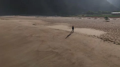 Aerial shot of a person's shadow walking along the sandy beach at Playa Stock Footage 287202855