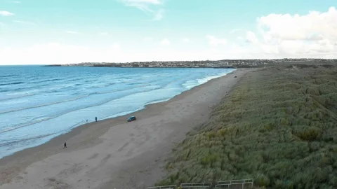 Aerial Shot pull away over some marram grass dunes along a beautiful beach Stock Footage 99069910
