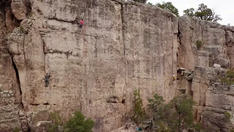 Aerial shot pulling away from a large rock wall where a climber is climbing Stock Footage 219430683