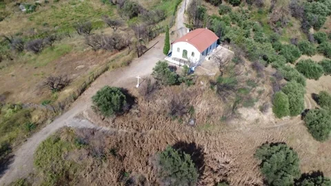 Aerial shot pulling back from a remote hilltop chapel and dirt road Stock Footage 344105312