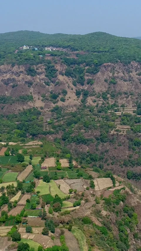 Aerial shot of rice fields on side of hill with steep rocky cliffs around Stock-Footage 226875865