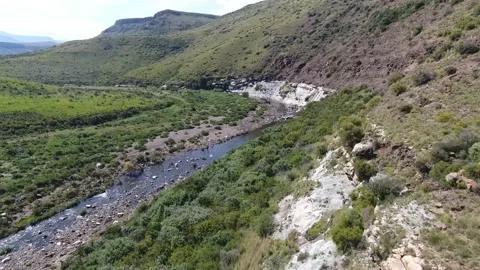 Aerial shot of river and stream surrounded by mountains and rolling hills Stock Footage 214356966
