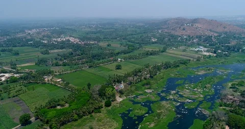 Aerial shot of river covered in algae, fields along and hill in background Stock-Footage 94453368