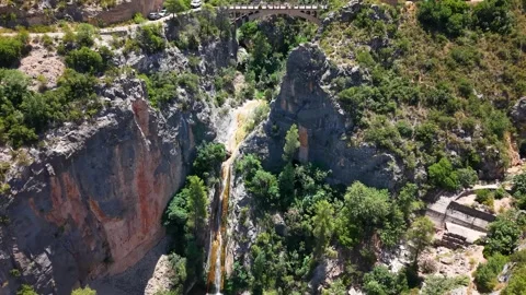 Aerial shot of a river flowing through canyons to an old, abandoned bridge Stock Footage 344054164