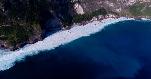 Aerial shot of rocky cliffs with waves breaking over shallow coral reef Video stock 99686892