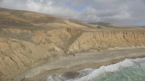 Aerial shot, rotating clockwise 40 ft over crashing waves onto ocean beach Stock Footage 90642793