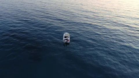 Aerial shot rotating over empty fishing boat surrounded by dark blue sea at Stock Footage 107779549