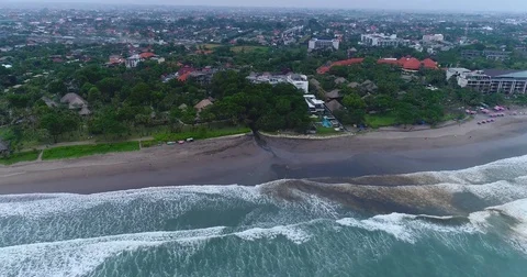 Aerial shot of Seminyak black sanded beach full of rubbish Stock Footage