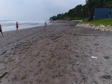 Aerial shot of Seminyak black sanded beach full of rubbish Stock Footage