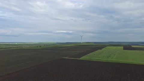 Aerial shot of a single rotating wind generator on rural agricultural fields Stock Footage 99329834