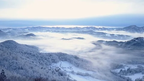 Aerial shot of Slovenia's snowy mountains and hills surrounded by fog Stock Footage