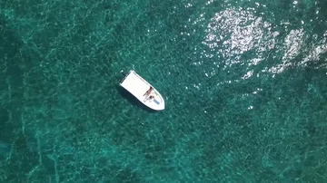 Aerial shot small boat clear water sea ocean blue while rotating lifting up Stock Footage
