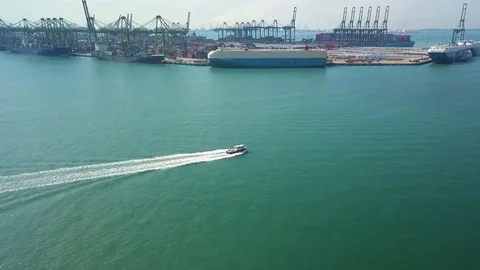 Aerial shot of small boat &amp; container ship leaving container port, Singapore Stock Footage 106081344
