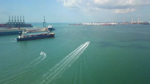 Aerial shot of small boat &amp; container ship leaving container port, Singapore Stock Footage 106081642