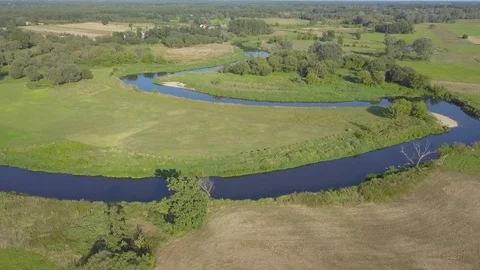 Aerial shot of small, curvy river on the green meadow. Vídeos de archivo 79622941