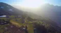 Aerial shot of small farming village on green hill of mountain in rays of sunset 4k or 4k+ Resolution