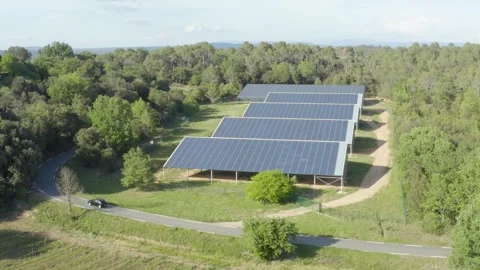 Aerial shot of a small solar panel farm in the forest with a car on a road Stock Footage 240960703