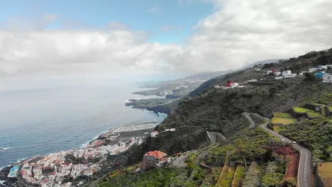Aerial shot. Small town at the base of the mountain, blue ocean and volcanic Stock Footage 104077103