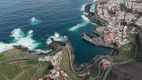 Aerial shot. Small town at the base of the mountain, blue ocean and volcanic Stock Footage 104348708