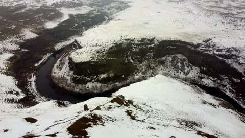 Aerial Shot of Steep Snowy Cliffs and River Gorge Bordering the Ancient City of Stock Footage 330880754