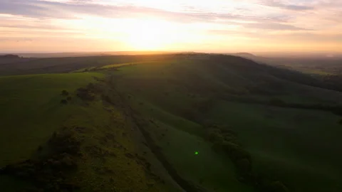 Aerial shot of the sunset over rolling green hills of the south downs Stock Footage 291672941