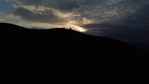 Aerial shot of sunset with white clouds and distant mountain silhouettes Stock Footage 287062685