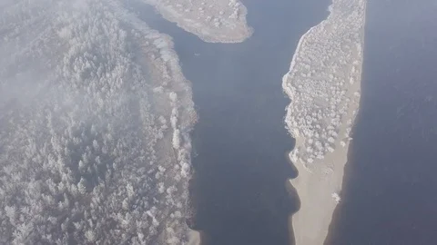 Aerial shot through clouds of winter islands and snowy trees in frost on river. Stock Footage 100468220