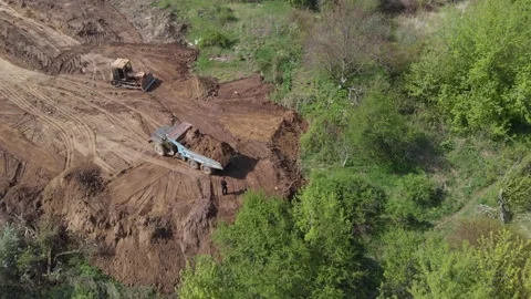 Aerial shot of tipper unloading ground on further construction site. Video stock 130221597