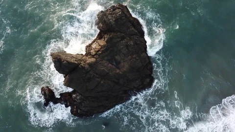 Aerial Shot Top Down Of Ocean With Big Rock Formation and Waves Crashing Stock Footage 128159185