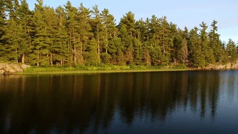 Aerial shot tracking left to right along lake shore low above water Stock Footage 112232629