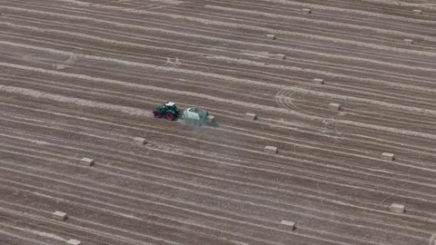 An aerial shot of a tractor pulling a baler across a large harvested field 库存影片 340848523