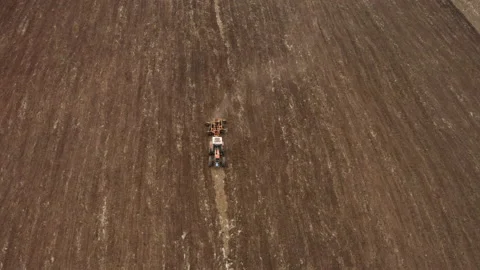 An aerial shot of a tractor pulling a spike harrow on a large agricultural field Stock Footage 142197699