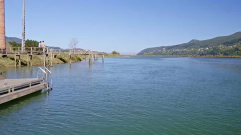 Aerial shot of two people on a footbridge over the river s Stock Footage