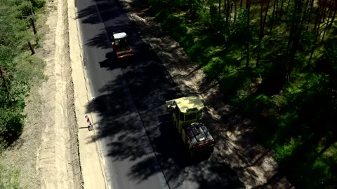 Aerial Shot Of Two Road Rollers Driving On An Empty Road In A Forest Stock Footage 142003924
