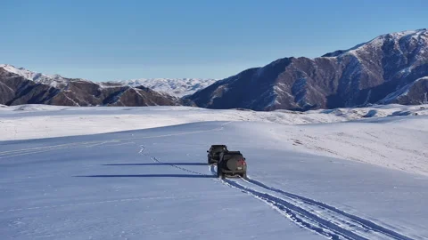Aerial shot of two suvs driving through a vast snowy Dzungarian Alatau mountain Stock Footage 321735662