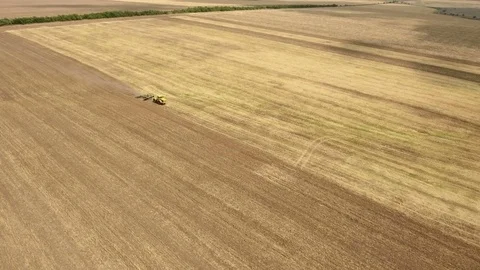 Aerial shot of a Ukrainian field and a farm tractor pulling a harrow in summer Stock Footage